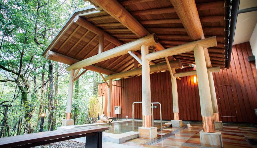 奥多摩温泉 もえぎの湯の露天風呂 木の屋根の下に湯船があり、屋根の奥には奥多摩の山の木々が見える